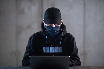 Image showing talented hacker using laptop computer while working in dark offi