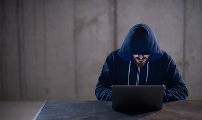 Image showing talented hacker using laptop computer while working in dark offi