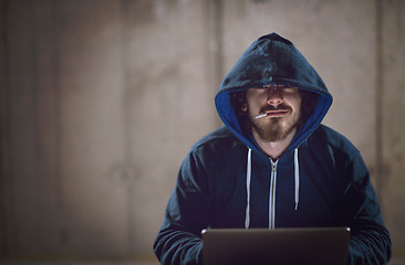 Image showing young hacker using laptop computer while working in dark office