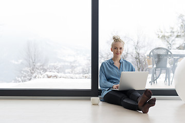 Image showing woman drinking coffee and using laptop at home