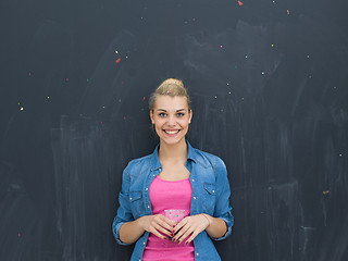 Image showing woman blowing confetti in the air isolated over gray