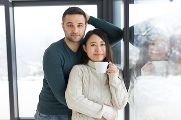 Image showing multiethnic couple enjoying morning coffee by the window