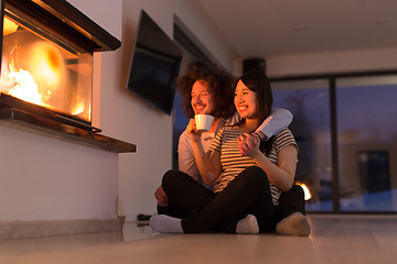 Image showing happy multiethnic couple sitting in front of fireplace