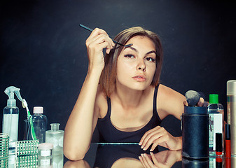 Image showing Beauty woman applying makeup. Beautiful girl looking in the mirror and applying cosmetic with a big brush.