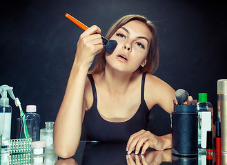 Image showing Beauty woman applying makeup. Beautiful girl looking in the mirror and applying cosmetic with a big brush.