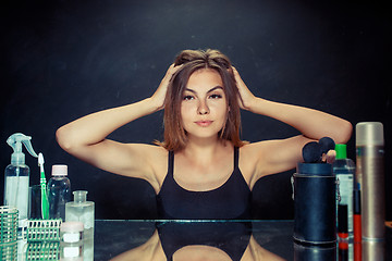 Image showing Beauty woman after applying makeup. Beautiful girl looking in the mirror and applying cosmetic with a brush.