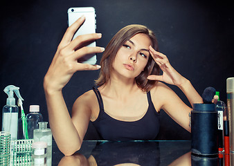 Image showing Beauty woman with makeup. Beautiful girl looking at the mobile phone and making selfie photo