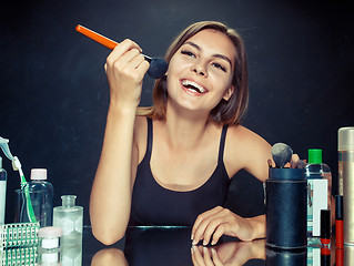 Image showing Beauty woman applying makeup. Beautiful girl looking in the mirror and applying cosmetic with a big brush.