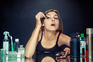 Image showing Beauty woman applying makeup. Beautiful girl looking in the mirror and applying cosmetic with a brush.