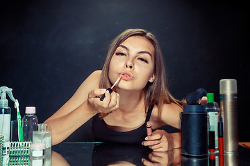 Image showing Beauty woman applying makeup. Beautiful girl looking in the mirror and applying cosmetic with a brush.
