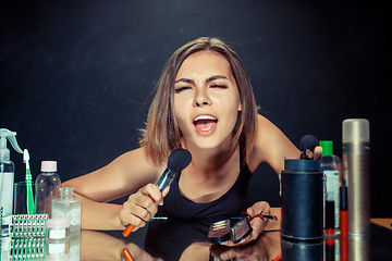 Image showing Beauty woman applying makeup. Beautiful girl looking in the mirror and applying cosmetic with a big brush.