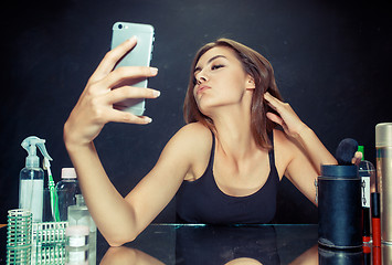 Image showing Beauty woman with makeup. Beautiful girl looking at the mobile phone and making selfie photo