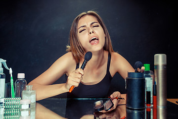 Image showing Beauty woman applying makeup. Beautiful girl looking in the mirror and applying cosmetic with a big brush.