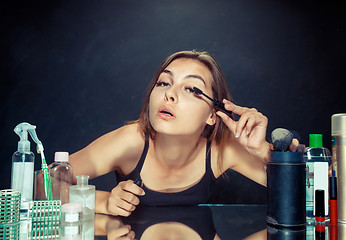 Image showing Beauty woman applying makeup. Beautiful girl looking in the mirror and applying cosmetic with a big brush.