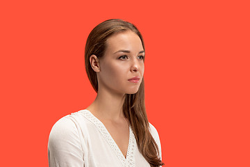 Image showing The serious business woman standing and looking at camera against red background.