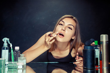 Image showing Beauty woman applying makeup. Beautiful girl looking in the mirror and applying cosmetic with a brush.