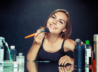 Image showing Beauty woman applying makeup. Beautiful girl looking in the mirror and applying cosmetic with a big brush.