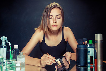 Image showing Beauty woman applying makeup. Beautiful girl looking in the mirror and applying cosmetic with a brush.