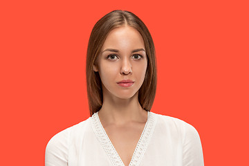 Image showing The serious business woman standing and looking at camera against red background.