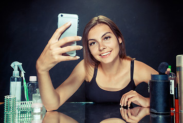Image showing Beauty woman with makeup. Beautiful girl looking at the mobile phone and making selfie photo