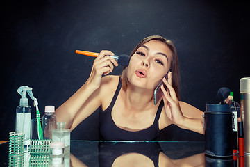 Image showing Beauty woman applying makeup. Beautiful girl looking in the mirror and applying cosmetic with a big brush.