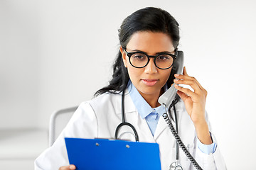 Image showing doctor with clipboard calling on phone at hospital