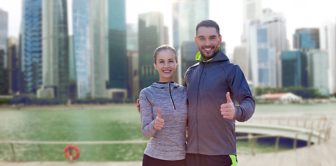 Image showing happy couple showing thumbs up over singapore city