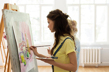 Image showing woman with easel painting at art school studio