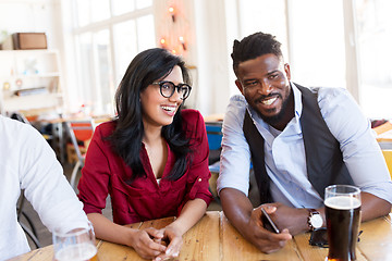 Image showing happy man and woman with smartphone at bar