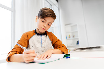 Image showing boy doing homework and writing to notebook at home