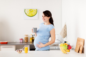 Image showing happy pregnant woman with cup at home kitchen