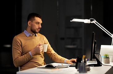 Image showing man with laptop and coffee working at night office