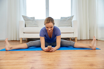 Image showing woman with smartphone doing yoga at home