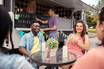 Image showing friends with drinks sitting at table at food truck