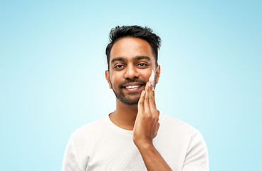 Image showing happy indian man applying cream to face