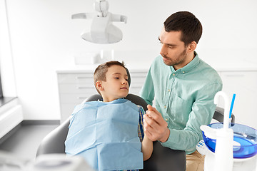 Image showing father supporting son at dental clinic