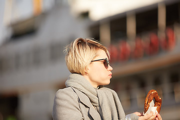 Image showing Young woman eating turkish bagel in Istanbul, Turkey. Traditional turkish street food.