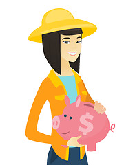 Image showing Young asian farmer holding a piggy bank.