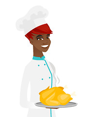 Image showing Young african chef holding roasted chicken.