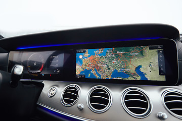 Image showing View from inside a car on a part of dashboard with a navigation unit and blurred street in front of a car