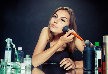 Image showing Beauty woman applying makeup. Beautiful girl looking in the mirror and applying cosmetic with a big brush.