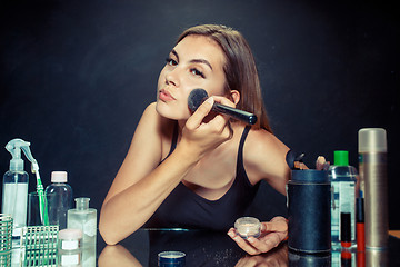 Image showing Beauty woman applying makeup. Beautiful girl looking in the mirror and applying cosmetic with a big brush.