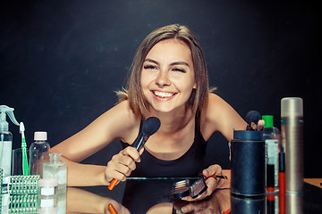 Image showing Beauty woman applying makeup. Beautiful girl looking in the mirror and applying cosmetic with a big brush.