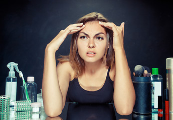 Image showing Unsatisfied young woman looking at her self in mirror on black background