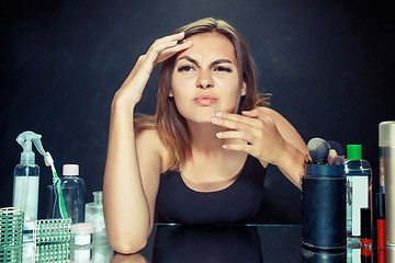 Image showing Unsatisfied young woman looking at her self in mirror on black background