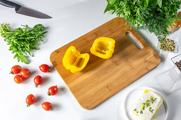 Image showing A set of vegetables, tomatoes, peppers, greens and cheese for a healthy salad on a white kitchen table with copy space. Top view