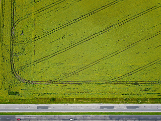 Image showing Aerial view from a drone on an agricultural field with a rural road along the field and cars on it. The view is strictly from above.