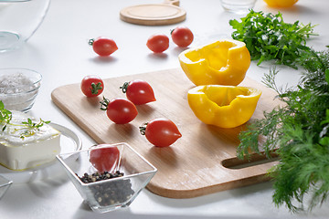 Image showing Ingredients for salad preparation, cheese, tomatoes, peppers, greens on a white kitchen table.