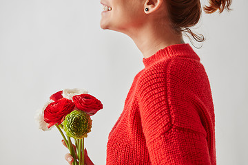 Image showing Happy girl in a red knitted sweater with a beautiful bouquet of brightly colored Ranunculus flowers around a gray background with copy space.