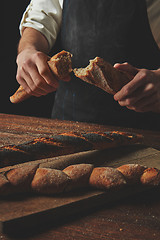 Image showing Male hands break the baguette